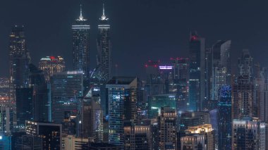 Dubai iş hangarının modern mimarisi ile gökyüzü çizgisi aydınlanan kulelerin tepesinde gece zaman dilimi. İnşaat alanı ile hava görüntüsü