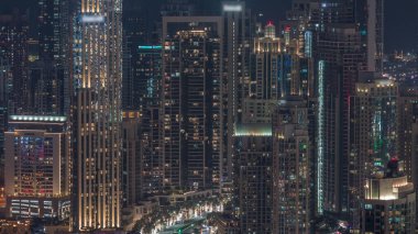 Muhammed Bin Rashid Bulvarı kıvrımlarındaki kavşak trafiği gece saatleri aydınlık gökdelenler ve kuleler arasında. Dubai şehrinin havadan görüntüsü iş sahasından yükselişe geçiyor.