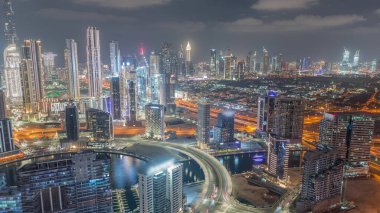 Dubai 'nin modern mimarisine sahip Skyline gece kuleleri aydınlatıyordu. Kanal ve inşaat alanı üzerinde kesişen ve köprü olan hava manzarası
