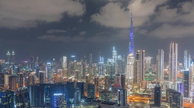 Dubai 'nin panoramik silueti, iş sahası ve şehir merkezi gece zaman çizelgesi. Birçok modern gökdelenin havadan görünüşü. Kanalda tekneler. Birleşik Arap Emirlikleri.
