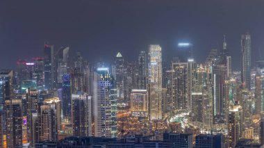 Dubai 'nin panoramik silueti, iş sahası ve şehir merkezi, eski kasaba evleri, gece zaman çizelgesi. Birçok modern gökdelenin havadan görünüşü. Birleşik Arap Emirlikleri.