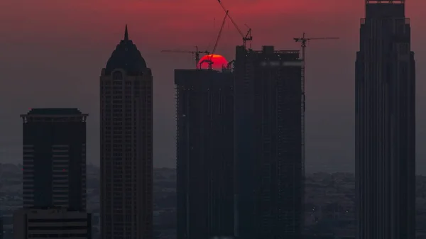 夕阳西下 迪拜商湾塔楼的现代建筑的天际线闪烁着红色的太阳 有运河和建筑工地的空中近景 — 图库照片