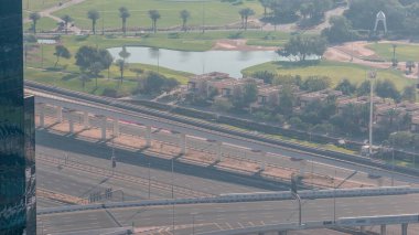 Golf sahasının havadan görünüşü yeşil çimenler ve göller, arkasındaki villalar zaman geçiyor. Otoyolda ve metro hattında trafik vardı. Dubai marina gökdeleninden en iyi manzara.