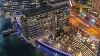 JBR ve Dubai Marina gökdelenleri, deniz kenarındaki modern gökdelenlerle birlikte gökdelenler, gece hava saatlerine göre apartmanlar. Yolda trafik vardı ve yürüyüş alanı yakındı.