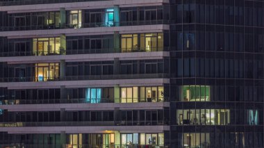 Modern ofisteki pencere ışıkları ve geceleri konut binaları. İçinde aydınlık daireler olan çok katlı gökdelenler.