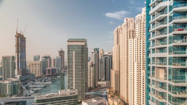 Havadan Dubai marina gökdelenlerine ve kanalın etrafındaki JBR kulelerine sabah saatlerinde yüzen teknelerle. Beyaz tekneler yat kulübüne park edilmiş. Sokakta trafik vardı.