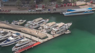 Dubai yat limanı kanalı hava manzaralı ve yüzen botlar zaman ayarlı. Beyaz tekneler yat kulübüne park edilmiş. Rıhtım yakınında su taksisi