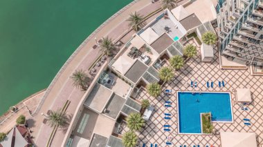 Kanal boyunca uzanan Dubai marinası kanalı boyunca palmiyeler ve mavi yüzme havuzu havuzu zaman ayarlı. Dubai 'nin modern yerleşim bölgesi manzaraya bak