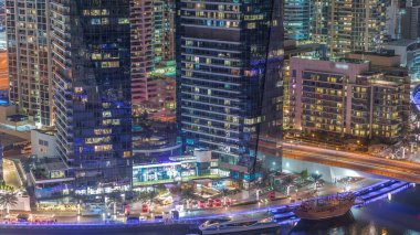 Dubai marinası gökdelenleri aydınlatıyordu. Rıhtımın yanında parlayan pencereler vardı. Kanal havası gece zaman çizelgesi boyunca. Dubai 'deki modern yerleşim bölgesi.