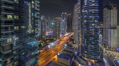 Dubai Marina ve JBR bölgesinin manzarası ve aydınlık gökdelenlerle dolu gece hava trafiği.
