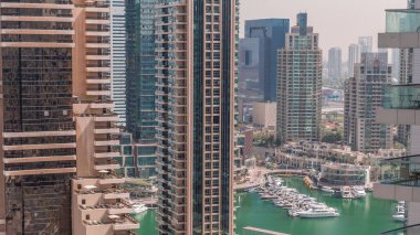 Dubai Marina gökdelenlerindeki hava manzarası ve liman zamanındaki en lüks yat. Yüzme havuzlu bir rıhtım üzerinde yürüme alanı boyunca kuleler. Dubai, Birleşik Arap Emirlikleri