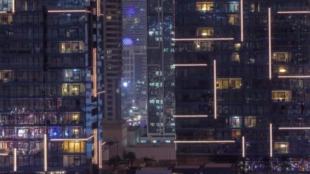 Panorama nocturno plano de luz multicolor en ventanas de edificios de varios pisos timelapse aéreo. — Vídeos de Stock