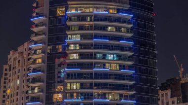 Gece vakitlerinde apartmanların pencereleri, balkonlu evlerin pencerelerinin ışığı. Parlak odalı şehrin akşam manzarası