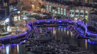Dubai Marina 'daki hava manzarası aydınlatılmış gezinti güvertesi ve liman gecelerinin en lüks yatı. Rıhtımdaki yürüme alanı boyunca kuleler. Dubai, Birleşik Arap Emirlikleri