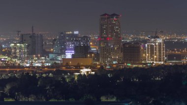 Dubai Creek hava sahasının yakınındaki gökdelenler ve kuleler aydınlandı. Avuç içleri ön planda park et