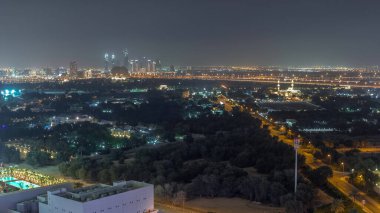 Zabeel bölgesindeki Bahçe, arka plandaki gökdelenler, Dubai, BAE 'deki hava zaman çizelgesi. Aydınlatılmış villaları ve camii olan caddelerde trafik