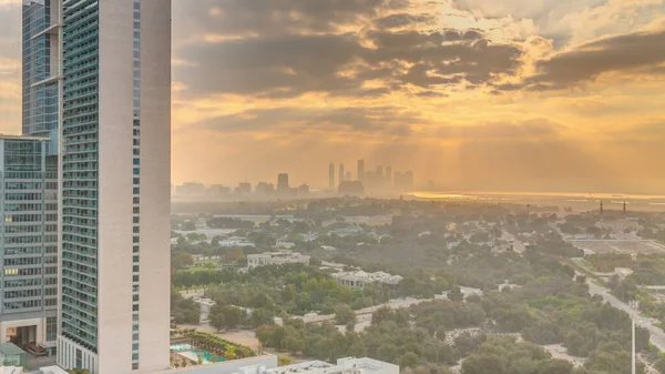 Zabeel bölgesinin bahçesinde gün doğumu, arka planda gökdelenler, Dubai, BAE 'de hava zaman aralığı. Gökyüzünde turuncu bulutlar ve güneş ışığı