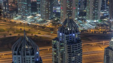Dubai Marina ve JLT semtleri gökdelenler arasında karayolu trafiği var. Aydınlatılmış modern kuleler ve otopark