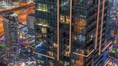 Gece manzarasına bakış açısı, lüks Dubai Marina gökdelenlerinin gece zaman çizelgesini vurguluyor. Dubai, Birleşik Arap Emirlikleri, parlayan camlı kulelerin arkasındaki otoyolda trafik