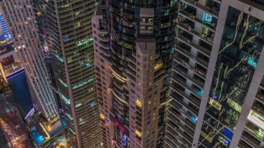 Gece manzarasına bakış açısı, lüks Dubai Marina gökdelenlerinin gece zaman çizelgesini vurguluyor. Parlayan pencereli kulelerin arkasındaki rıhtım, Dubai, Birleşik Arap Emirlikleri