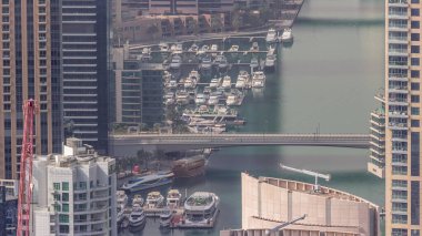 Dubai Marina 'nın kıyı şeridi boyunca gökdelenlerle çevrili yapay kanalların üzerindeki köprüyü gösteren yakın görüntüsü. Limandaki yatlar ve tekneler. Dubai, BAE