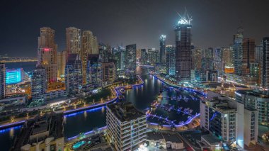 Dubai Marina 'da limana park etmiş birkaç tekne ve yatı var. Kanal havası çevresindeki gökdelenleri aydınlatıyorlar. JBR bölgesi ve şantiye panoramik manzarasının kuleleri