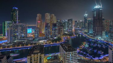Dubai Marina 'da liman panoramik manzarasına parketmiş birkaç tekne ve yat var. Kanal anteninin çevresindeki aydınlık gökdelenler. Arka planda JBR bölgesi kuleleri