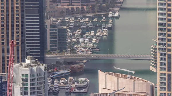 Dubai Marina 'nın kıyı şeridi boyunca gökdelenlerle çevrili yapay kanalların üzerindeki köprüyü gösteren yakın görüntüsü. Limandaki yatlar ve tekneler. Dubai, BAE