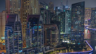 Dubai Marina 'da rıhtıma yakın teknesi ve kanalın etrafında aydınlık gökdelenleri var. Arka planda JBR bölgesi kuleleri