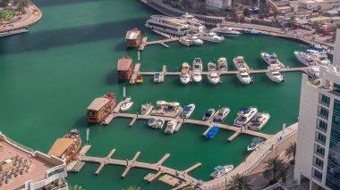 Birçok yat ve tekne liman havası zaman dilimine park edilmiştir. Dubai Marina rıhtımı yürüyüş alanı. Modern tekne derede yüzüyor..