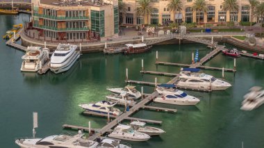 Dubai Marina hava sahasına yanaşmış lüks tekne ve yatlar. Limandaki rıhtım boyunca parkedilmiş sürat tekneleri. Güneş suya yansıyor