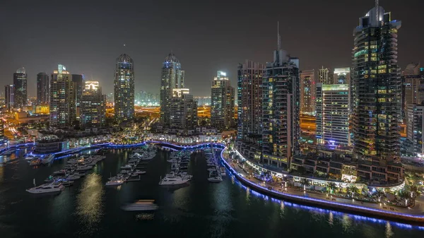Dubai marinasındaki havadan gece saatlerinde lüks yat körfezi panoraması. Rıhtım boyunca modern gökdelenler ve limanda yüzen tekneler.