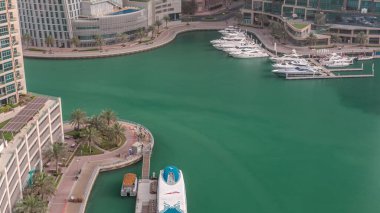 Dubai Marina 'da avuçiçi avuçlarla rıhtım gezintisi. İnşaatçılar su taşıma istasyonunun yakınındaki geçidi tekrarlıyorlar. Yatlar ve tekneler suda yüzüyor.