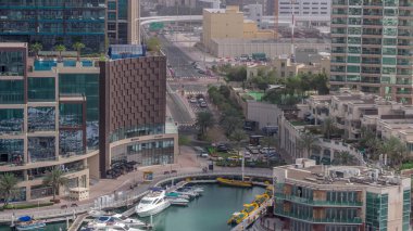 Dubai Marina 'da avuçiçi avuçlarla rıhtım gezintisi. Yatlar ve tekneler suyun üzerinde yüzüyor. Kavşağın yakınındaki kavşakta trafik vardı.