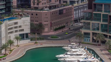 Dubai Marina 'da avuçiçi avuçlarla rıhtım gezintisi. Yatlar ve tekneler suyun üzerinde yüzüyor. Yolda trafik vardı.