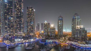 Dubai Marina turistik bölgesi, gökdelenleri ve kanalı çevreleyen kuleleri var. Parlak pencereli gizli binalar. Yatlar suda yüzüyor.