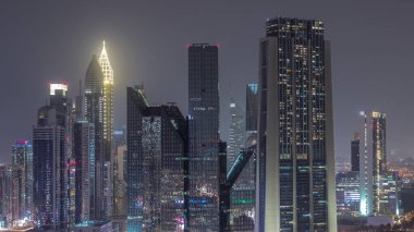 Dubai Finansal Merkezi 'nin gece saatlerinde aydınlatılan gökdelenleri olan yakın görüntüsü. Yoğun karayolu boyunca kulelerin hava görüntüsü