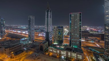 Gökyüzü görüntüsünden Dubai şehir merkezindeki gökdelenlere. Modern mimari gece aydınlanır. Arka planda şehir yürüyüş bölgesi
