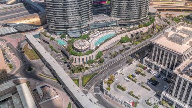 Dubai şehir merkezindeki otelin yakınındaki çatı yüzme havuzu. Beyaz şemsiyeler ve güneşlikler. Ofis binalarının yakınındaki bir yolda trafik vardı.