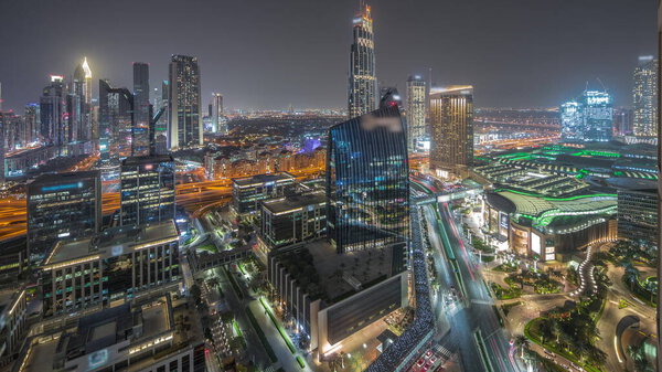 Futuristic Dubai Downtown and finansial district skyline aerial night timelapse. Many illuminated towers and skyscrapers with traffic on streets near shopping mall