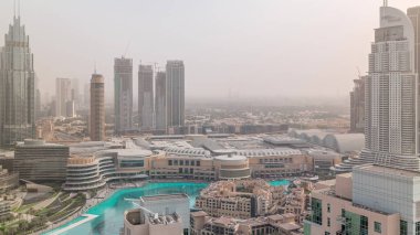 Dubai şehir merkezinde fıskiyeler ve modern fütüristik mimari hava zaman ayarlarıyla. Sis ve alışveriş merkezlerindeki gökdelenlere bak