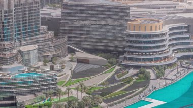 Dubai şehir merkezinde fıskiyelerin yanında alışveriş merkezi ve modern fütüristik mimari hava zaman dilimi ile. Avuç içleriyle yürüme alanına yakın görünüm