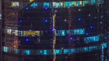 Modern kuledeki ofis pencereleri gece saatlerinde yanıp sönüyor. İçinde aydınlık odalar olan çok katlı gökdelenler..