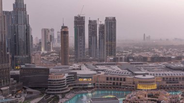 Dubai şehir merkezinde fıskiyeler ve modern fütüristik mimari gece gündüz geçiş zamanı. Finans bölgesi ve alışveriş merkezi olan gökdelenlere bak