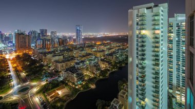 Barsha Heights bölgesindeki gökdelenler ve Greenens bölgesindeki alçak binalar gece panoramik zaman çizelgesi. Pencerelerinde ışıklar olan Dubai silueti
