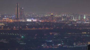 Deira ve Dubai deresi bölgesindeki evlerin ve otellerin hava manzarası. Tipik eski ve modern binaların gece zaman çizelgesi. Dubai, Birleşik Arap Emirlikleri