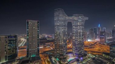 Panorama fütüristik Dubai şehir merkezi ve finans bölgesi gökyüzü gece zaman çizelgesini gösteriyor. Birçok aydınlık kule ve gökdelenler caddelerde trafik var.