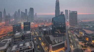 Fütürist Dubai Şehir Merkezi ve finans bölgesi gökyüzü gece gündüz geçiş zamanı. Birçok aydınlık kule ve gökdelenler güneş doğmadan önce sabah sisi ile