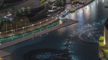 Dubai gezinti güvertesi havadaki mimari zaman ayarının arka planında şarkı söyleyen fıskiyeler. Alışveriş merkezinin yakınındaki gösteriyi izleyenler