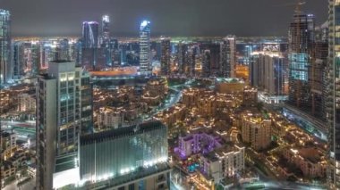 Aerial panoramic view of a big futuristic city night timelapse with traffic on intersection. Business bay and Downtown district with many skyscrapers and traditional houses, Dubai, United Arab